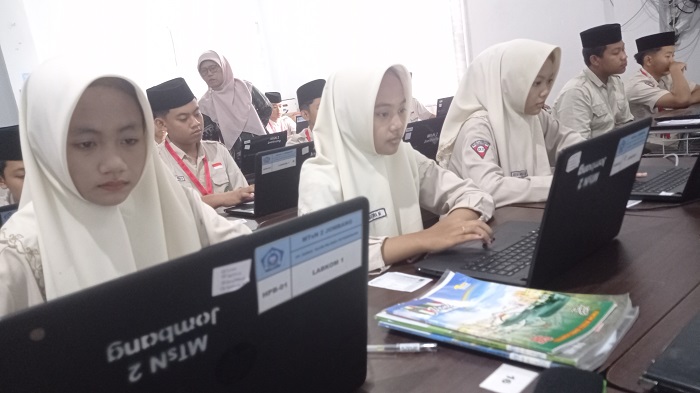 SERIUS: Kepala MTsN 2 Jombang, Agustin Aminah, memantau siswa mengerjakan tryout TKA di laboratorium komputer , Kamis (5/2).  
