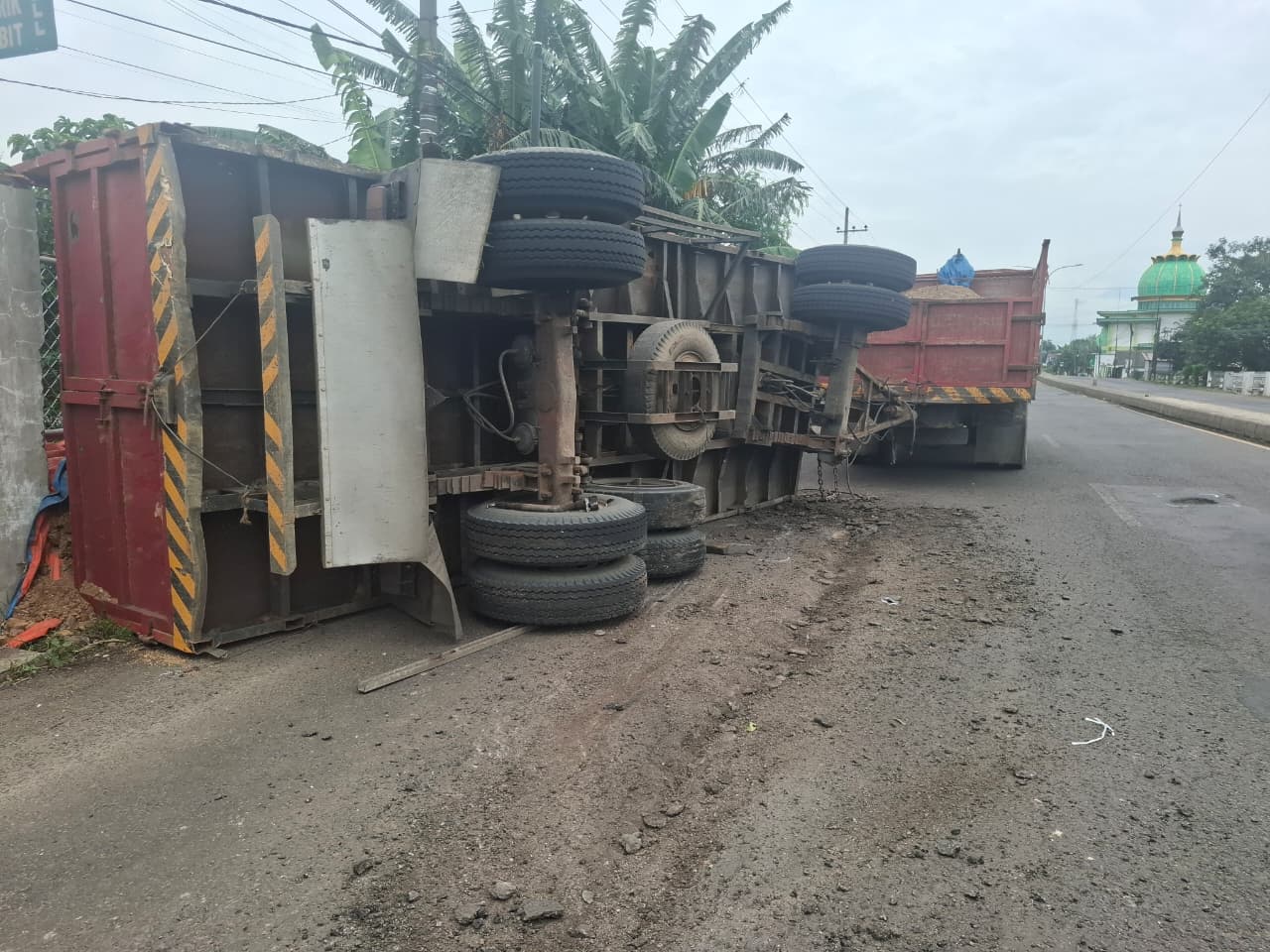 Sebuah truk gandeng ambruk di jalan nasional Desa Palrejo, Kecamatan Sumobito usai as rodanya patah usai terjerembab lubang jalan Selasa (24/2) pagi.
