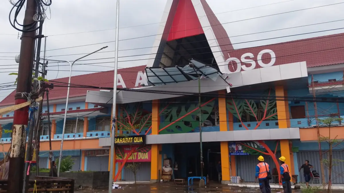 Hujan deras disertai angin kencang mengakibatkan neon box bertuliskan Pasar Ploso dan kaca berbentuk segitiga di bagian atas pintu masuk pasar ambruk, Senin (30/3).