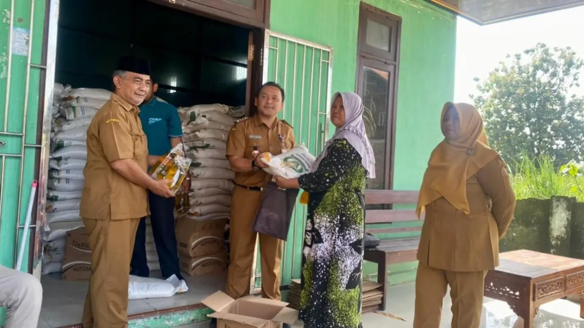 UNTUK WARGA: Kepala Desa Gondek Hisbulloh Huda (paling kiri) mendampingi Camat Mojowarno M Ronny Afriandie memberikan bantuan pangan secara simbolis kepada salah satu warga, Selasa (14/4).