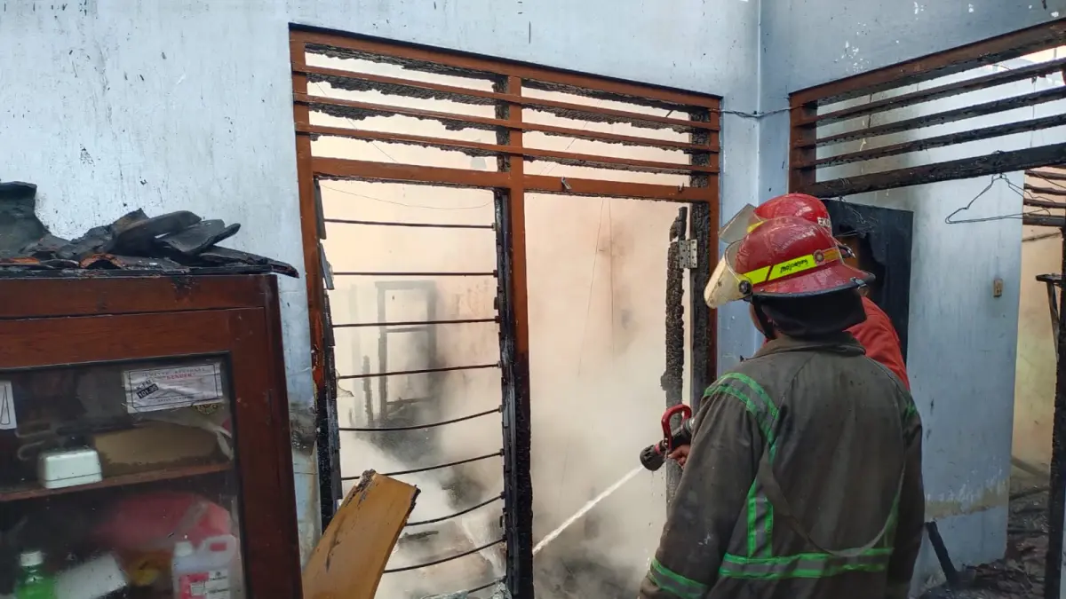 Petugas pemadam kebakaran saat melakukan pembasahan di rumah korban