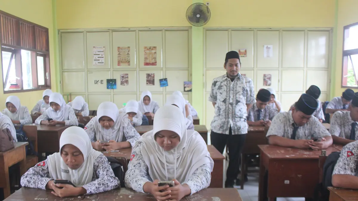 SABAR: Guru MTsN 9 Jombang saat memantau siswa mengerjakan tryout TKA di lab komputer (5/2).