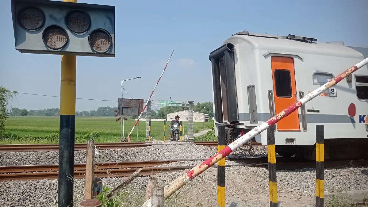 TUNGGU KERETA: Warga melintas di perlintasan KA Desa Nglele, Kecamatan Sumobito yang diusulkan dibangun palang pintu.