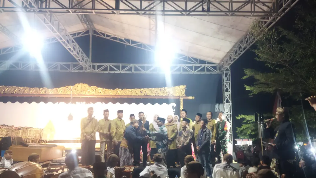 SIMBOLIS: Kepala Desa Karangwinongan Iknan menyerahkan wayang secara simbolis kepada Ki Dalang Tatut Sutanto saat acara sedekah desa, Selasa (16/6) malam.