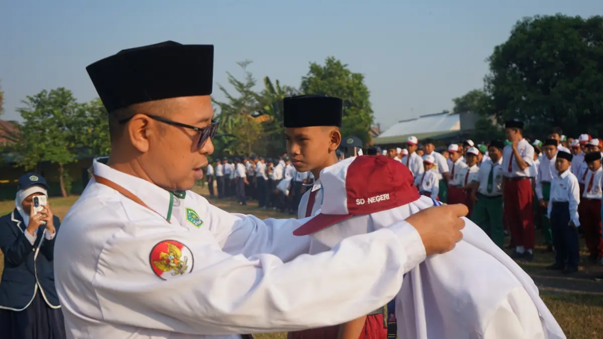 SIMBOLIS: Kepala MTsN 11 Jombang, HM Makhi, memberikan tanda peserta secara simbolis kepada siswa baru, (13/7). 
