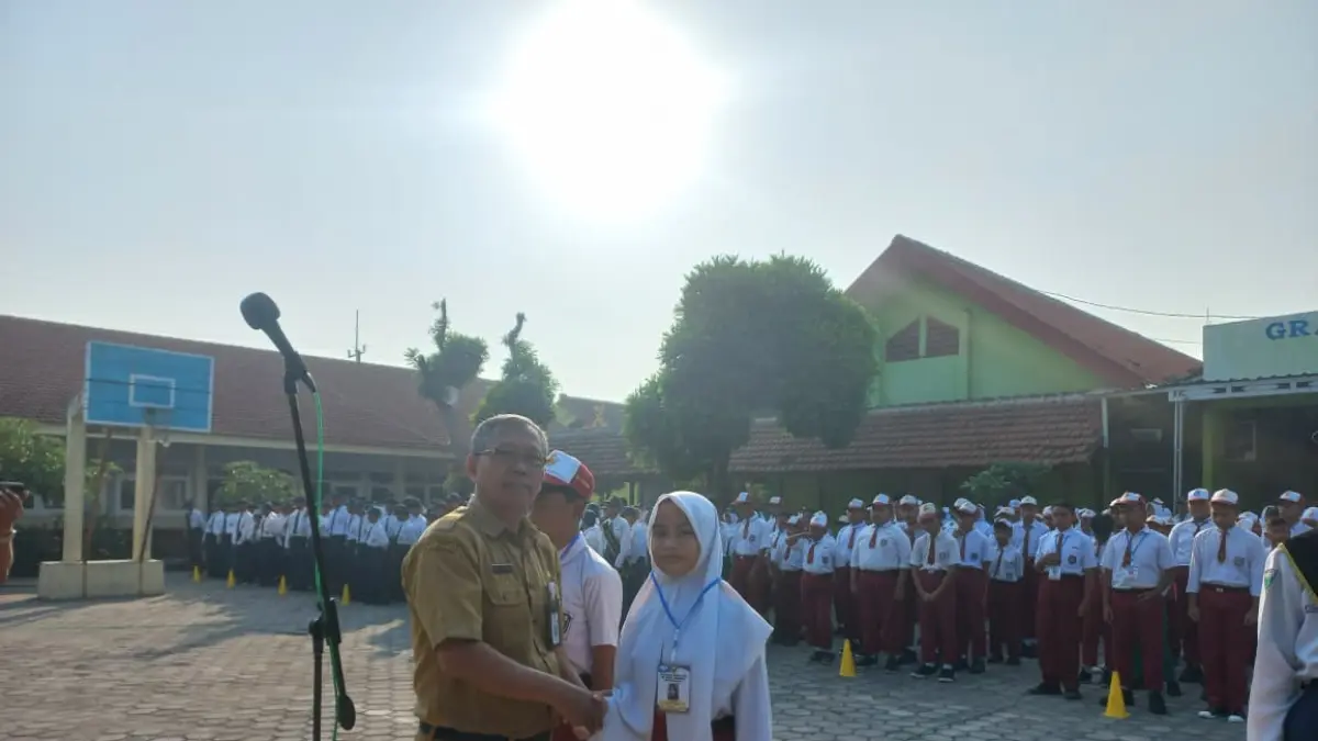 INOVATIF: Kepala SMPN 2 Mojowarno, Muji Suwanto SPd, menyematkan identitas peserta kepada perwakilan murid baru saat pembukaan, Senin (13/7) pagi.