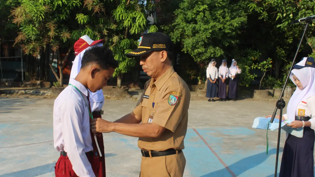 MEMBANGGAKAN: Kepala SMPN 2 Plandaan, Drs Bambang Setiyawan MEd, menyematkan id card kepada perwakilan murid baru saat pembukaan MPLS, Senin (13/7) pagi.