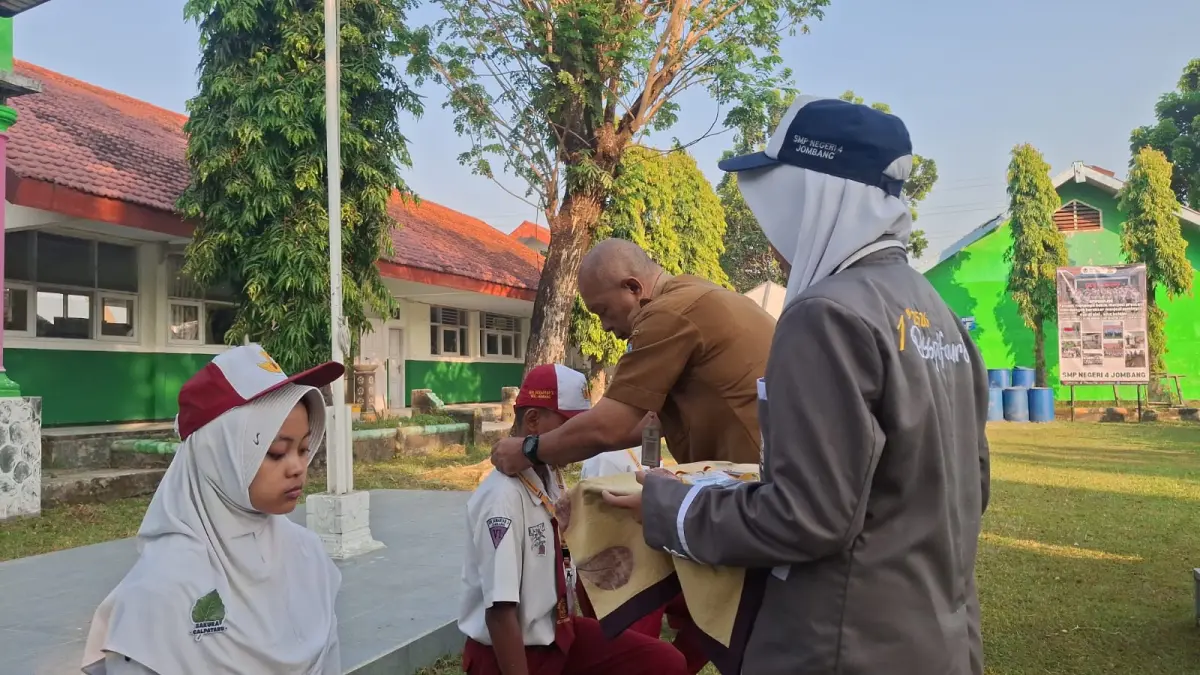RAMAH: Kepala SMPN 4 Jombang, Slamet Agus Tri Prastyo SPd, mengalungkan id card kepada perwakilan murid baru saat upacara pembukaan MPLS Senin (13/7) pagi.