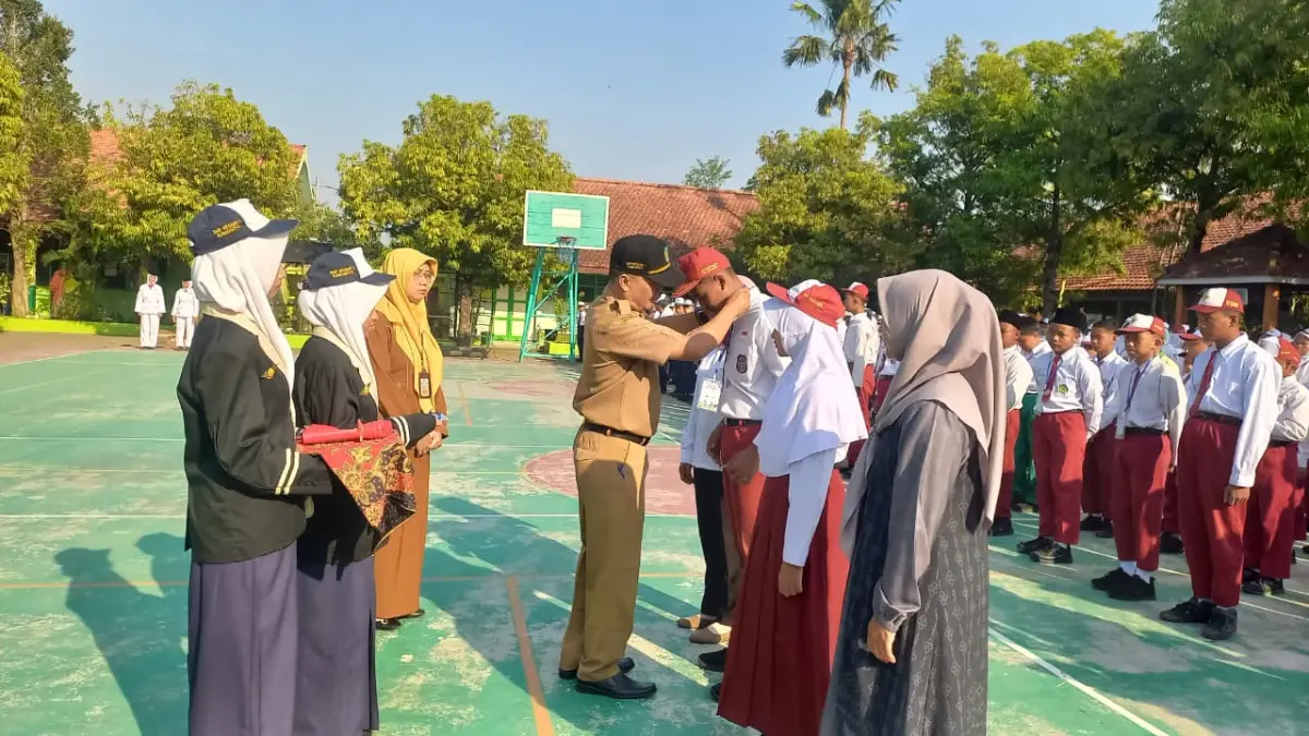 TELADAN: Kepala SMPN 1 Sumobito, Sugeng Hariyanto MPd, menyematkan identitas peserta saat pembukaan MPLS, Senin (13/7) pagi.