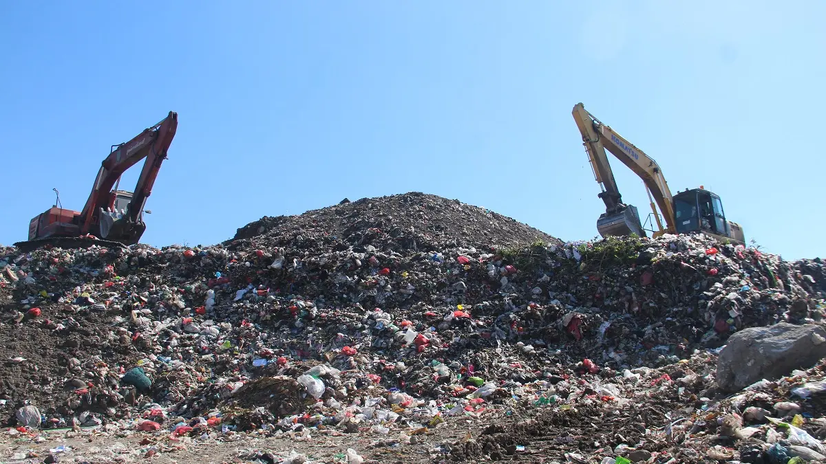 MENGGUNUNG: Dua alat berat mengurai gunungan sampah di TPA Banjardowo kemarin (15/7).