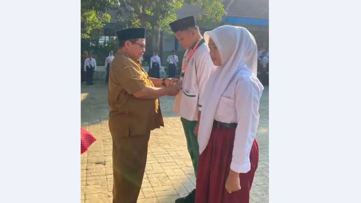 SEMANGAT: Kepala SMPN 2 Mojoagung, Sugeng Wibowo MPd, menyematkan tanda peserta MPLS kepada siswa baru, Senin (13/7).