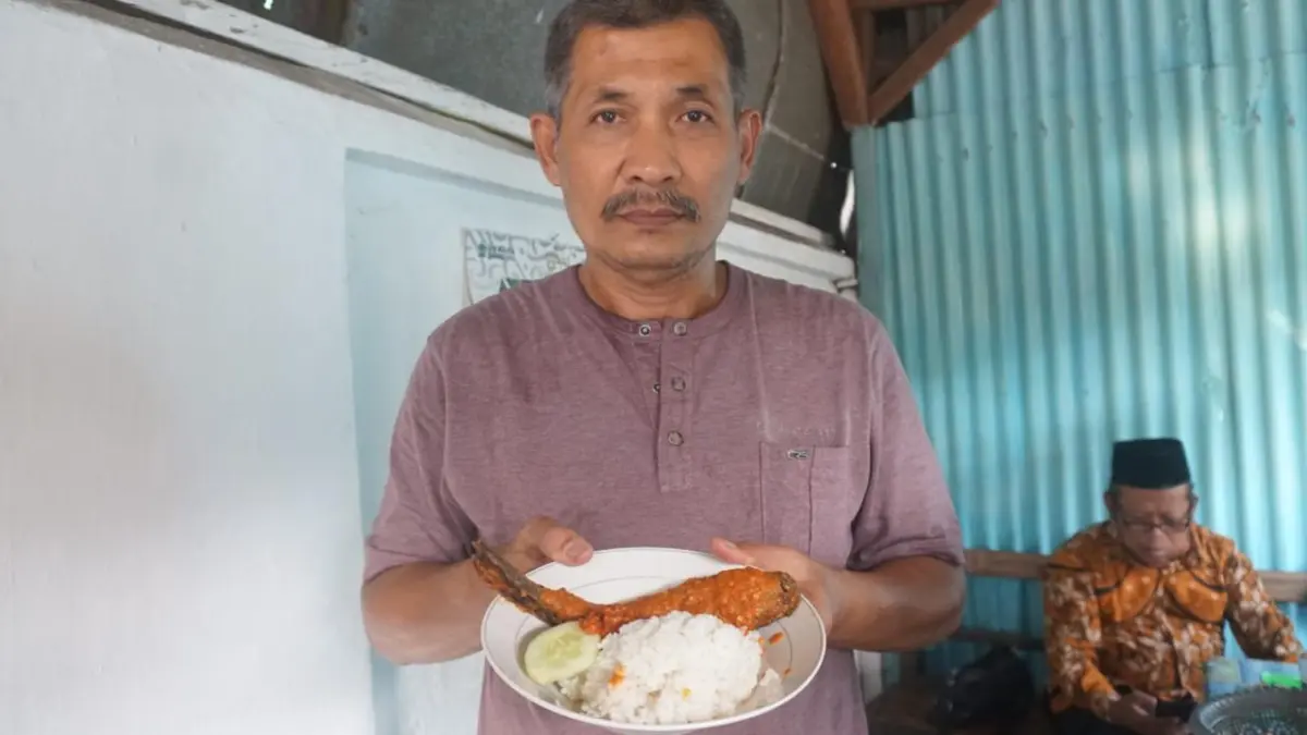 RESEP WARISAN KELUARGA: Ahmad Syafi’i menunjukkan seporsi menu andalan ikan lele bumbu rujak Warung Bu Jujuk di Dusun Tambakberas Gang IV, Desa Tambakrejo, Kecamatan/Kabupaten Jombang.&nbsp;