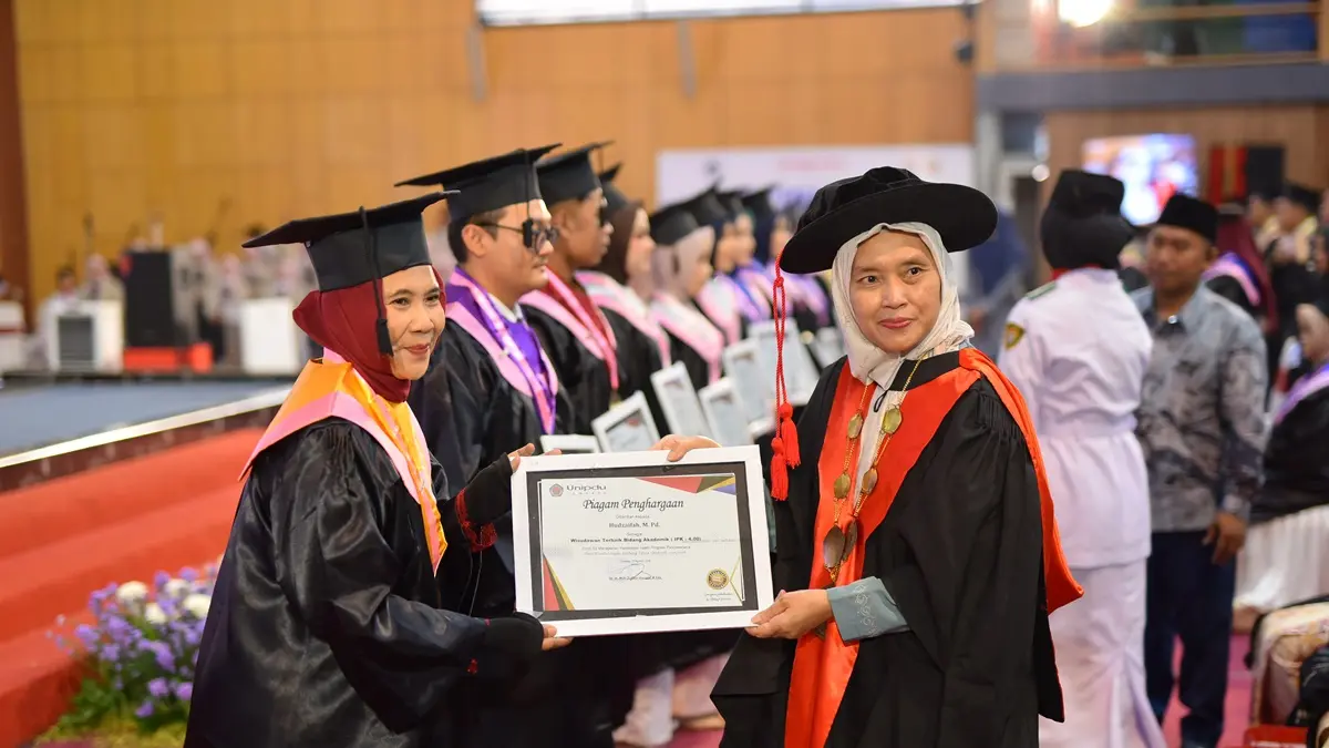 APRESIASI: Wakil Rektor Bid. SDM, Keuangan & Umum (Hj. Uswatun Qoyyimah, S.S., M.Ed., Ph.D) saat penyerahan cinderamata kepada wisudawan terbaik akademik.

