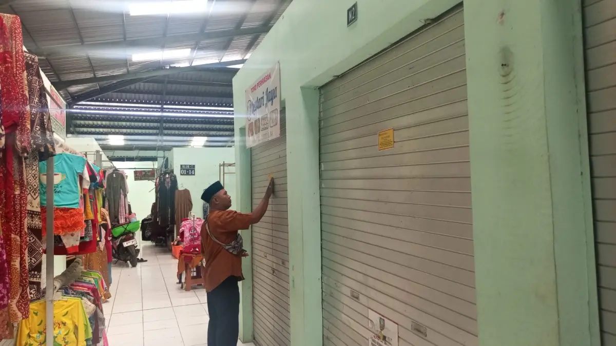 DISEGEL LAGI: Petugas menempel stiker segel di kios Pasar Perak yang tutup lama, Kamis (27/8).