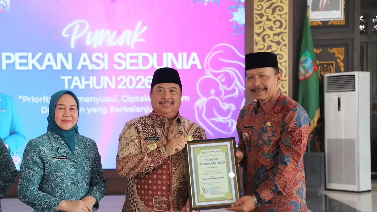 APRESIASI: Bupati Jombang Warsubi didampingi Ketua TP-PKK Kabupaten Jombang Yuliati Nugrahani Warsubi memberikan piagam penghargaan kepada Kepala Desa Gedangan Sukarno saat acara puncak Pekan ASI Sedunia 2026 di Pendopo Kabupaten Jombang, Kamis (10/9) siang.