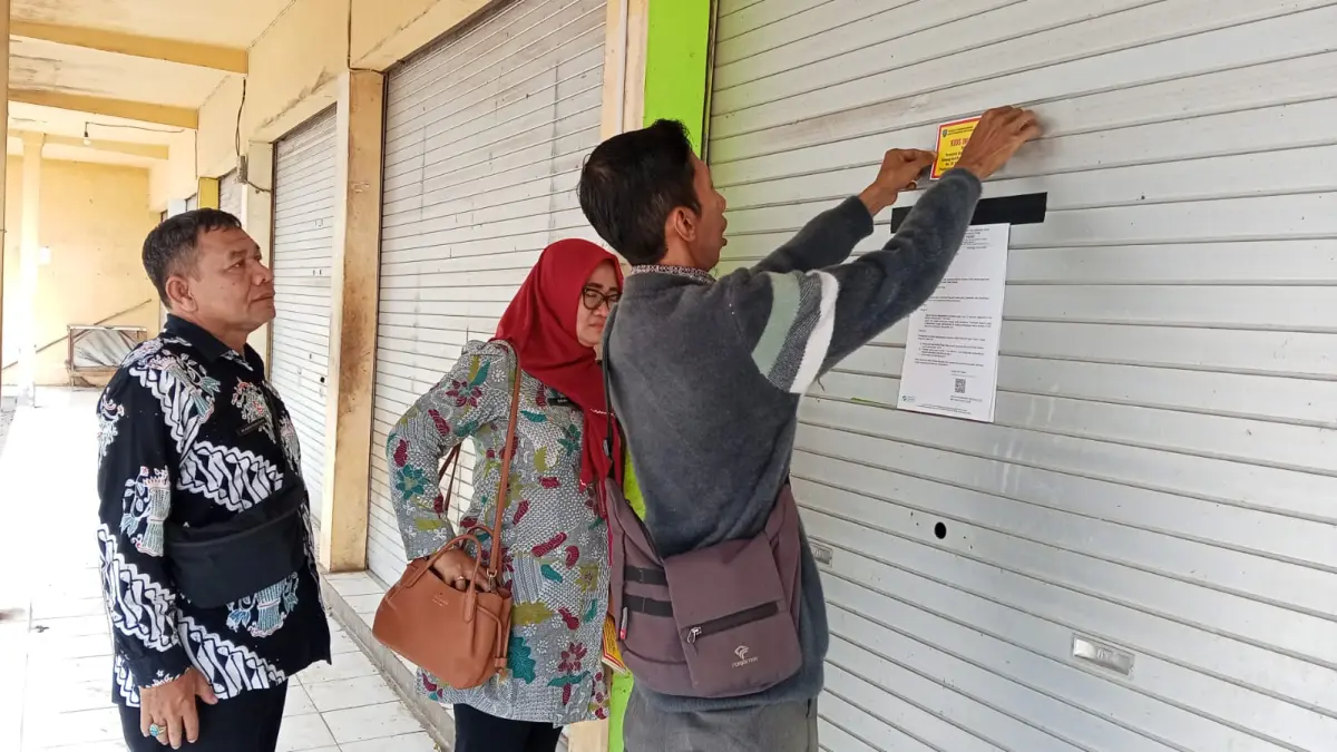 FOTO: AZMY ENDIYANA/JAWA POS RADAR JOMBANG

&nbsp;

DISEGEL: Petugas memasang stiker segel pada kios yang tutup dan tidak digunakan untuk berjualan.