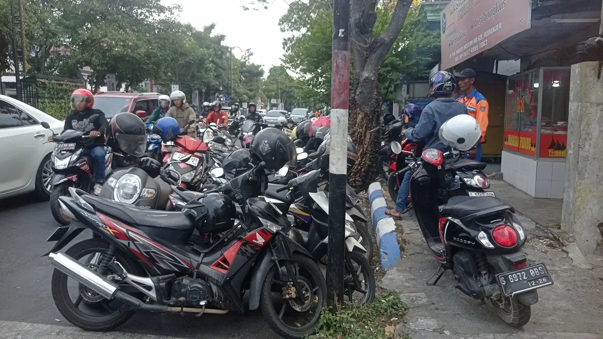PENUH: Jukir di Jl KH Wahid Hasyim menata kendaraan roda dua yang terparkir hingga ke trotoar.