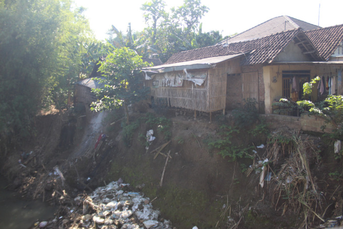 Rumah warga di Desa Betek, Kecamatan Mojoagung makin menggantung dan doyong ke sungai. Tanggul sungai Gunting yang rusak belum juga diperbaiki, (ANGGI FRIDIANTO/JAWA POS RADAR JOMBANG)