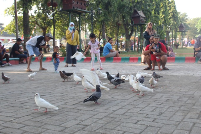 Sejumlah anak ditemani orang tua asyik memberi makan burung di sekitar Alun alun Jombang, kemarin (6/8). (ANGGI FRIDIANTO/JAWA POS RADAR JOMBANG)