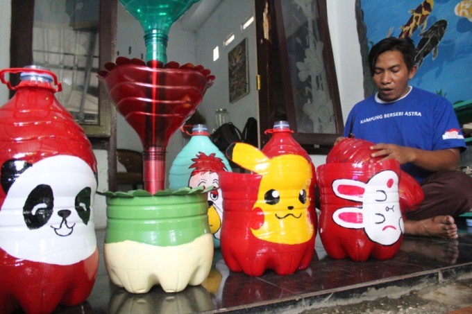 Adi Kusuma, saat mengolah galon bekas jadi aneka pot bunga cantik.