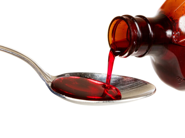 A bottle of cold medicine poured into a spoon