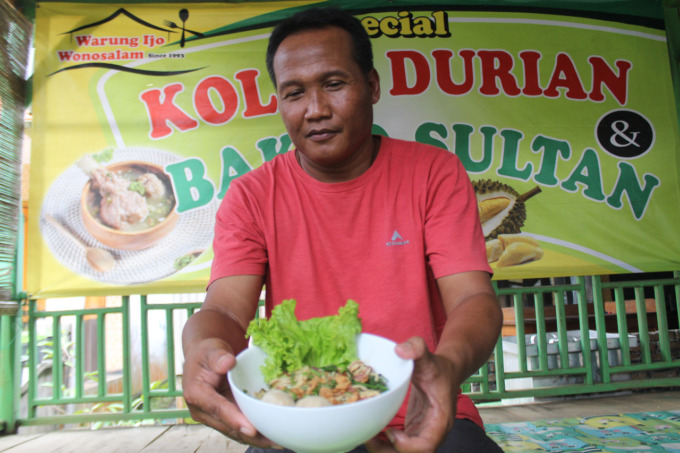 Dwi Cahyo Utomo, 65, warga Dusun/Desa Panglungan, Kecamatan Wonosalam mengolah mi kuah hitam kluwek di warungnya kemarin.