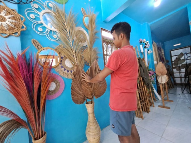 Firdaus Hakim, sedang menata hasil karya dekorasi rustik di rumahnya.
