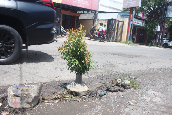 Kerusakan bahu Jl Kapten Tendean Jombang membuat warga memasang pot agar tak menjebak pengendara.