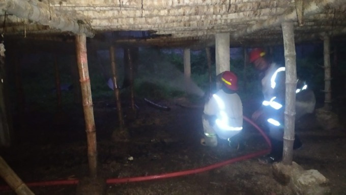 Petugas pemadam kebakaran tengah melakukan pembasahan pada kandang ayam yang terbakar di Dusun Juwet, Desa Glagahan, Kecamatan Perak.