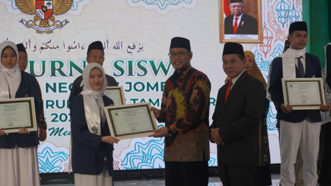 Kepala MAN 3 Jombang, Sutrisno bersama Ketua Yayasan PPBU menyerahkan piagam kepada salah satu wisudawan berprestasi