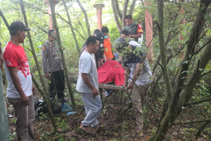petugas kepolisian dibantu warga saat mengevakuasi jasad korban dari lokasi kejadian