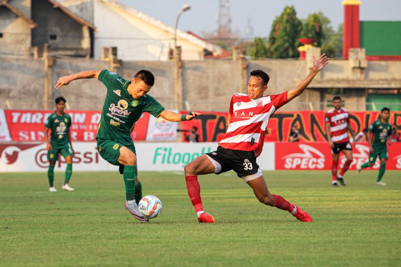 Pemain Persebaya Surabaya Sho Yamamoto (kiri) berupaya melewati hadangan pesepak bola Madura United FC Koko Ari Araya (kanan) pada pertandingan BRI Liga 1 di Stadion Gelora Bangkalan.