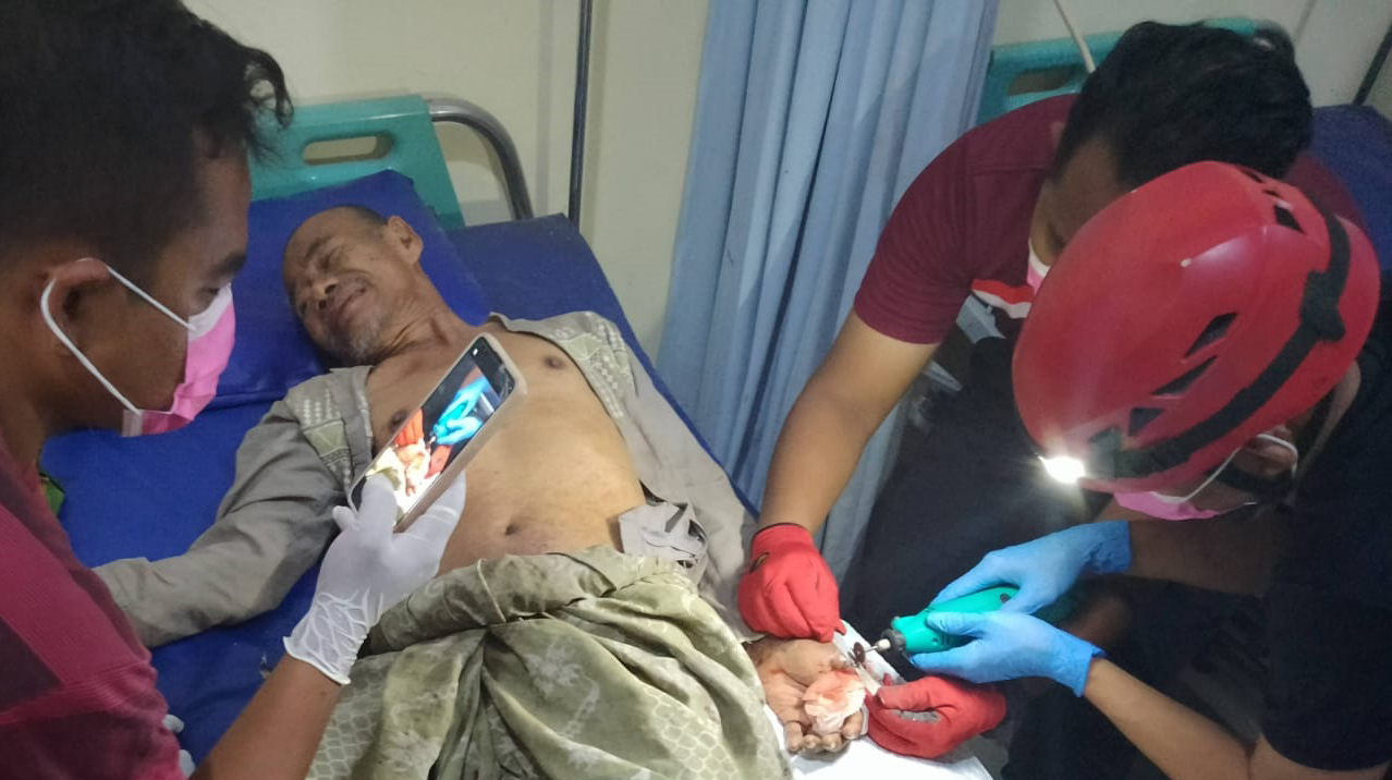 EVAKUASI: Petugas Satpol PP dan Damkar saat melakukan pemotongan cincin yang melilit di jempol lansia.