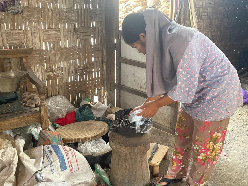 MEMBUNGKUS AMPO: Salah satu pelestari makanan khas Tuban berbahan tanah liat saat mengambil dari tempat pembakaran.