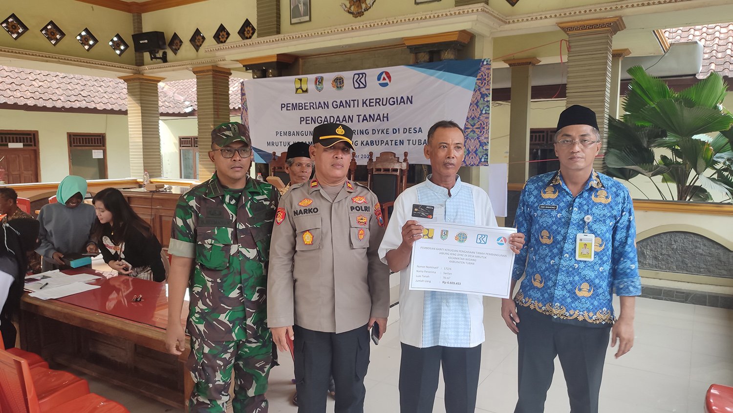 BUKTI PENYERAHAN: Salah satu penerima ganti rugi proyek pembangunan Jabung Ring Dyke di Desa Mrutuk, Kecamatan Widang berpose bersama kapolsek, perwakilan koramil, dan BPN Tuban.