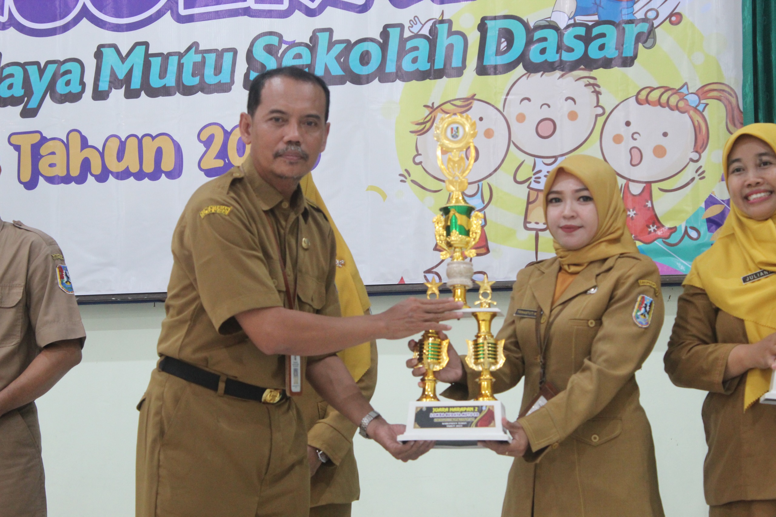 MENGAPRESIASI: Kabid Pengelolaan Pendidikan Sekolah Dasar Disdik Tuban Mokhamad Nurdin, S.Pd., M.Pd, menyerahkan piala kepada salah satu juara lomba budaya mutu SD di aula Disdik, Senin (11/12).
