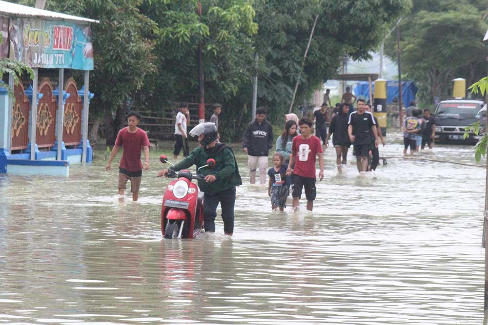TETAP MELINTAS: Meski jalan digenangi air, warga Desa Sawahan, Kecamatan Rengel tetap melintas menggunakan kendaraan roda duanya.