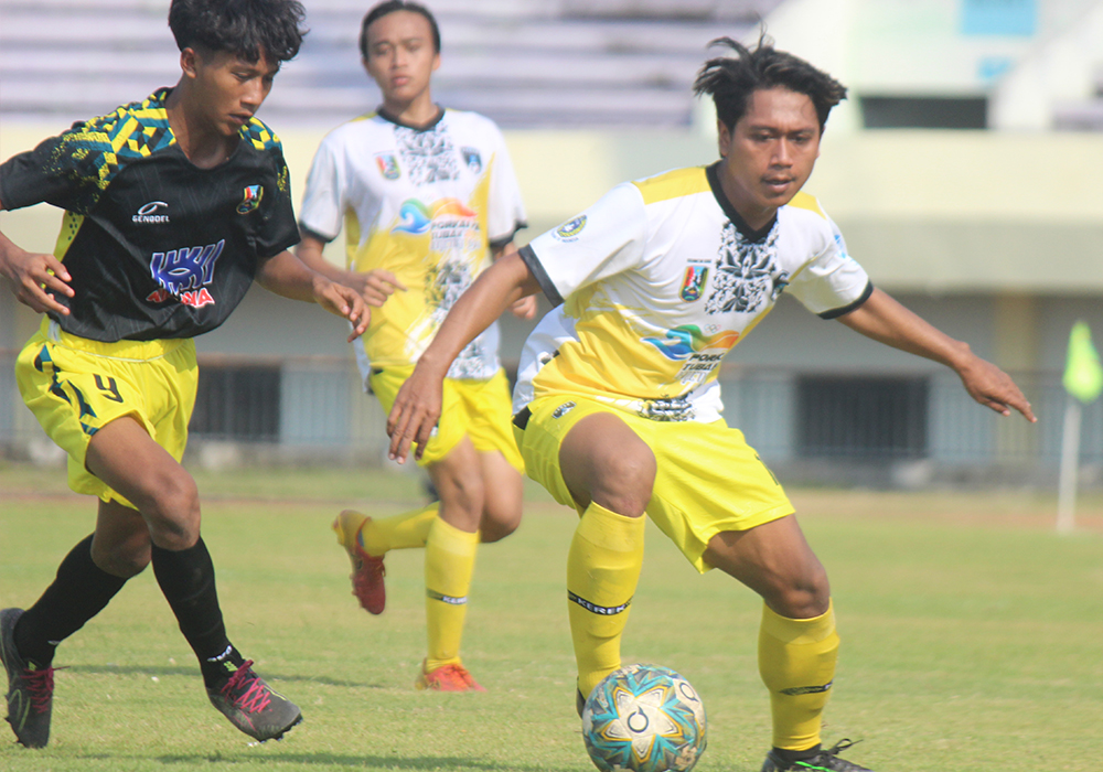 Aksi pemain Kecamatan Plumpang saat berusaha mengamankan bola dari kejaran pemain Kecamatan Kerek dalam pertandingan penyisihan grup C Porkab VIII Tuban cabor sepakb