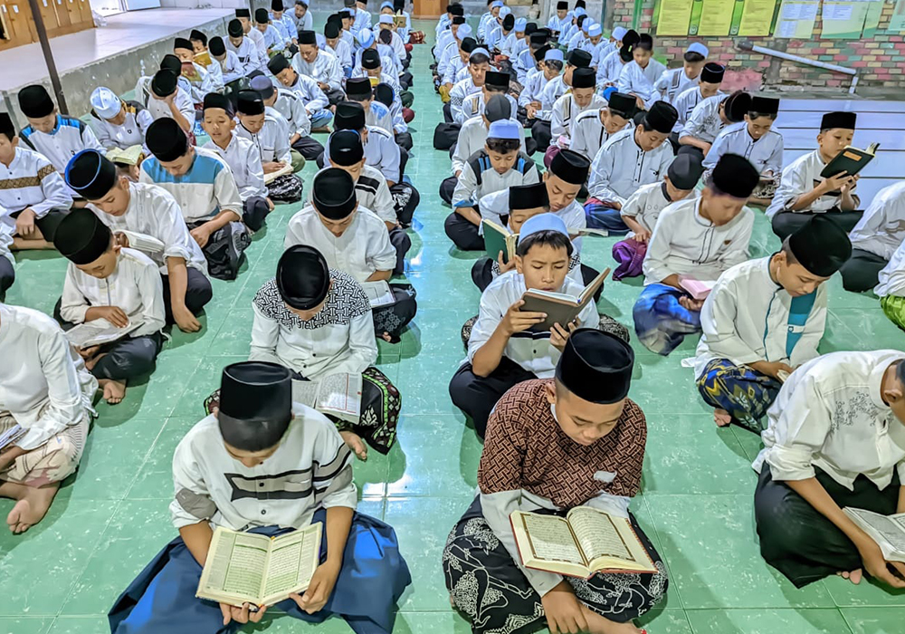 Santri putra dan putri berbaris membaca Alquran sebelum setoran bacaan ke ustad pendamping.