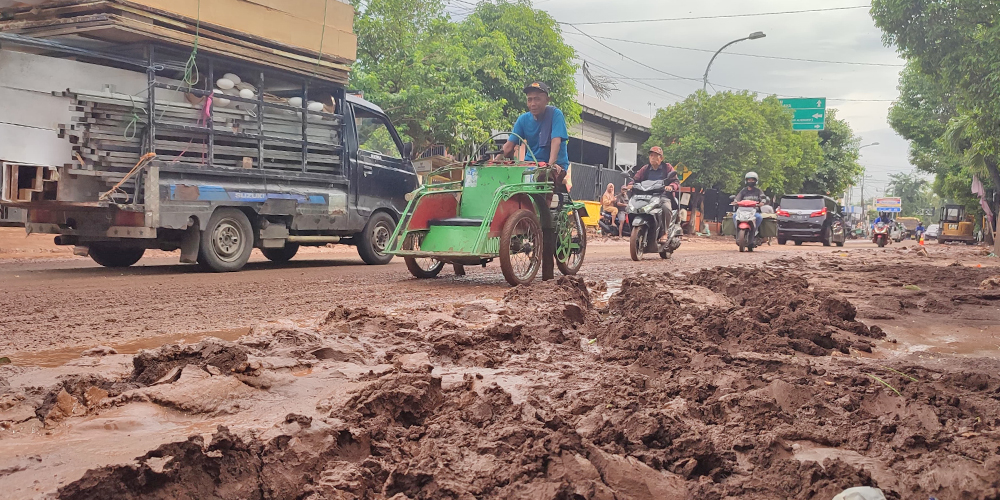 Lumpur sisa material banjir bandang menggenangi jalan raya depan Pasar Desa/Kecamatan Rengel, Minggu (5/1)