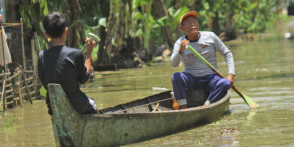 Salah satu warga Desa Kanorejo, Kecamatan Rengel melintasi jalanan yang tergenang banjir menggunakan perahu, Kamis (27/2).