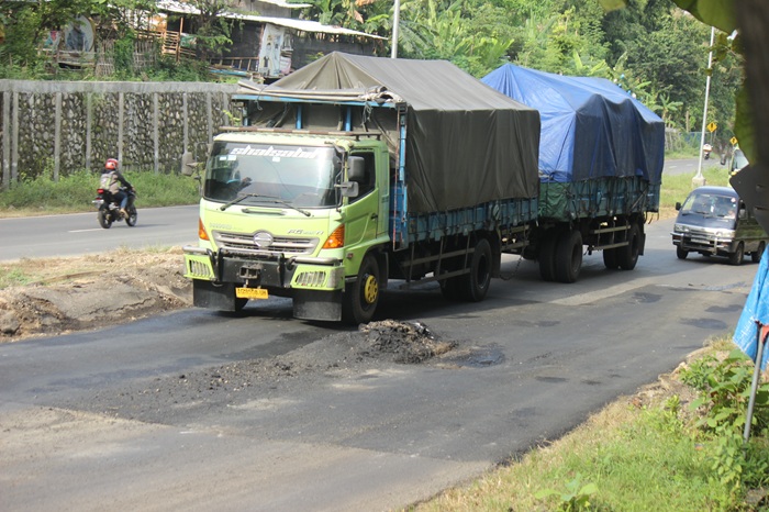 Salah satu kendaraan muatan berat terpaksa harus mengurangi kecepatan akibat kondisi jalan rusak di JLS Tuban, kemarin (4/5).