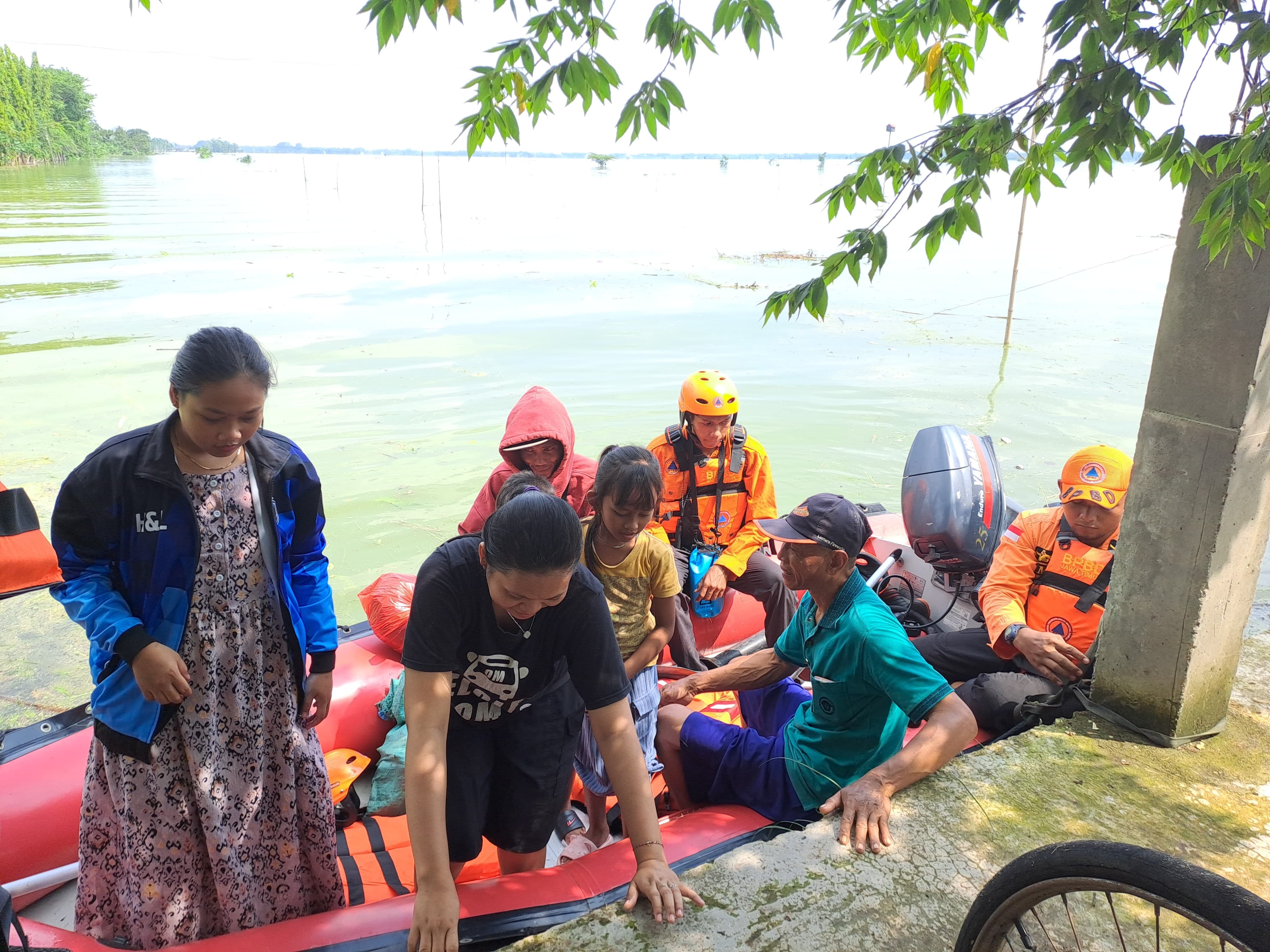 Warga Desa Kanorejo, Kecamatan Rengel menaiki perahu karet BPBD Tuban akibat akses jalan tergenang banjir, kemarin (21/5).