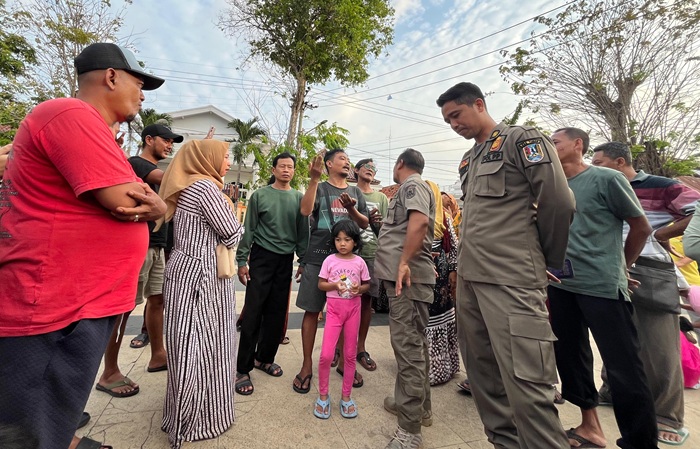 PKL menghadapi anggota Satpol PP yang mencoba memperingatkan agar tidak berjualan di trotoar depan pintu masuk Makam Sunan Bonang.