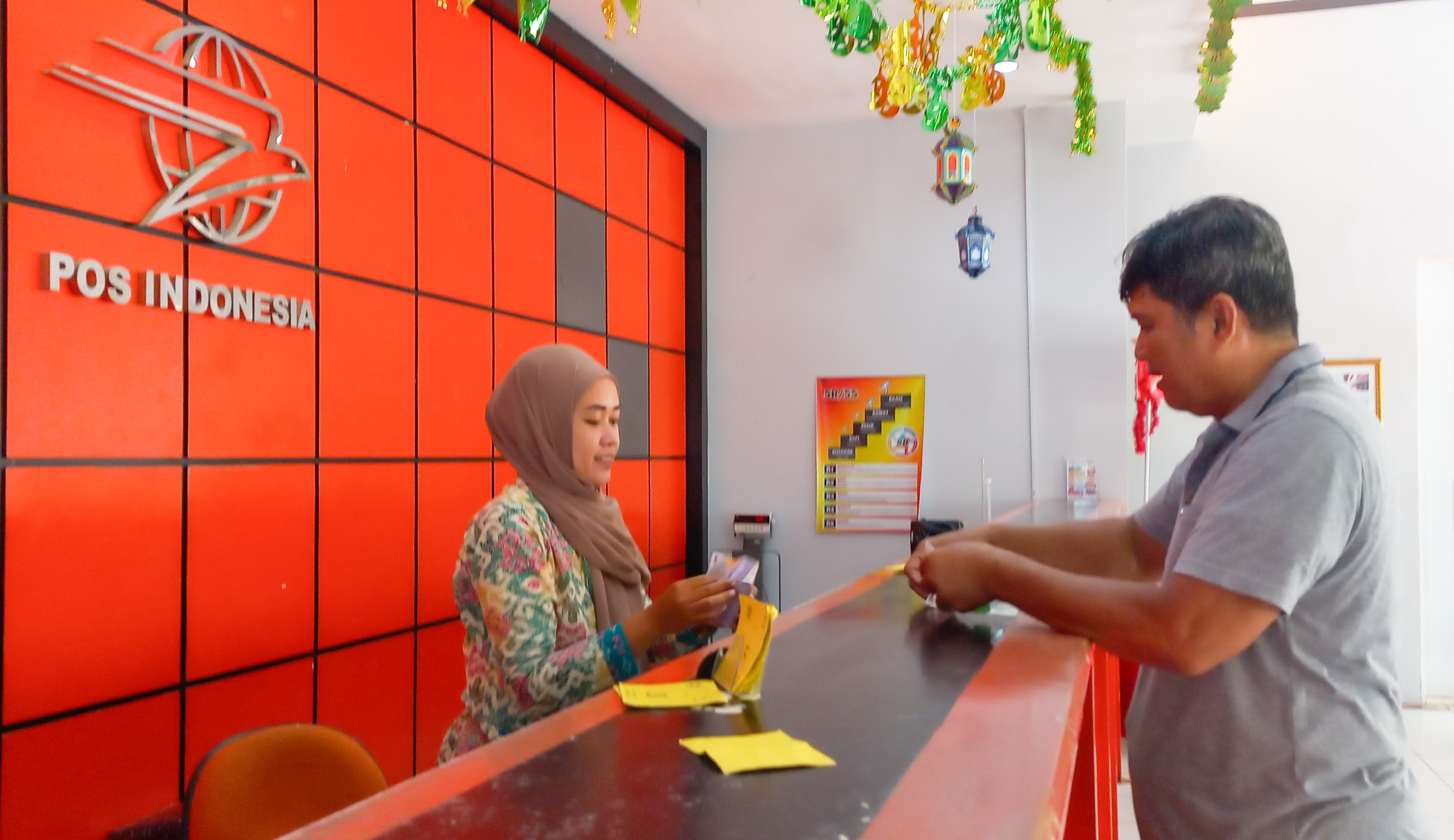 Salah seorang petugas pelayanan di Kantor Pos Tuban tengah sibuk melayani customer, kemarin (8/8)