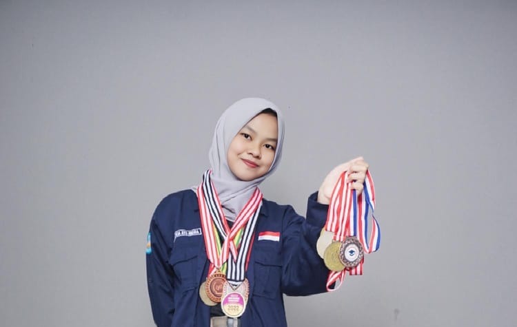 Ayu berfoto dengan sumringah sembari memegang banyak medali yang diperolehnya.