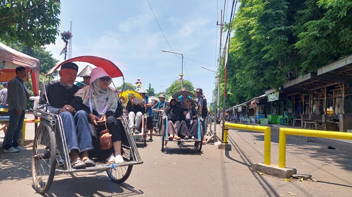 MENUNGGU KETEGASAN: Pengayuh becak menunggu penumpang di area Parkir Wisata Kebonsari