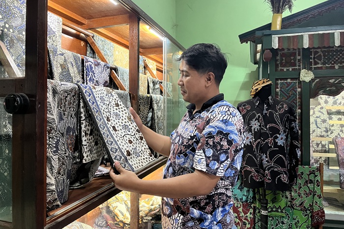 Donny tengah memeriksa salah satu produk batik tulisnya yang menggantung rapi di etalase galerinya di Kelurahan Karang, Kecamatan Semanding.