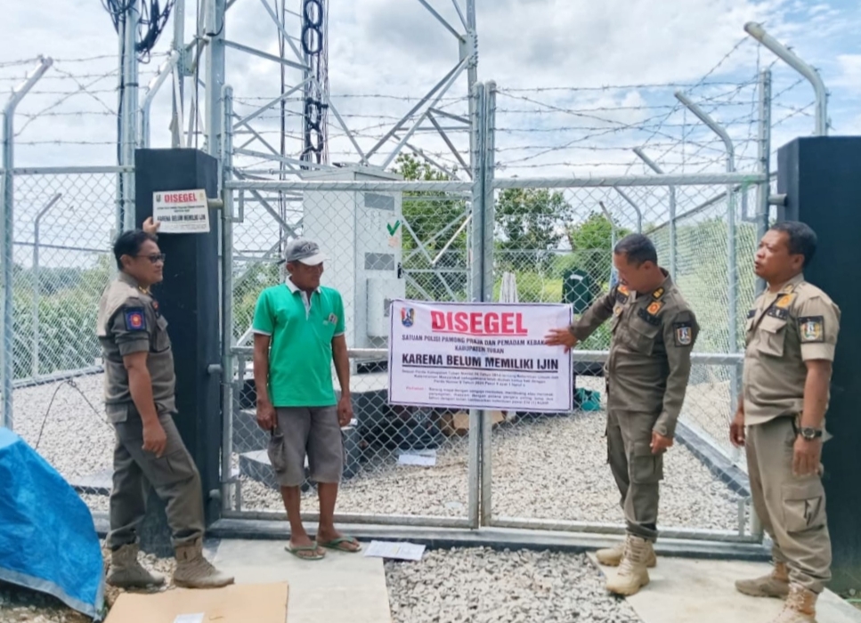Petugas Satpol PP dan Damkar Tuban menyegel menara telekomunikasi yang diduga ilegal di Desa Dagangan, Kecamatan Parengan, Selasa (6/1).