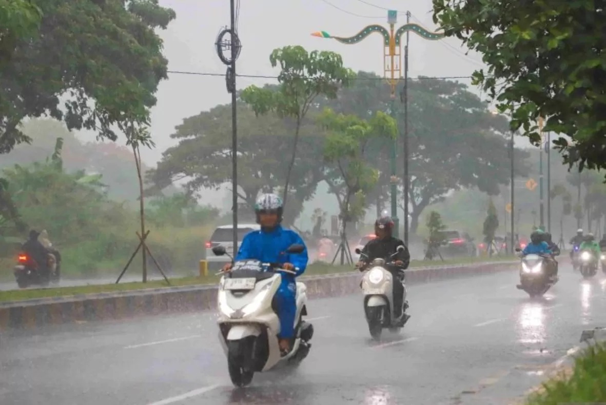 Pesepeda motor berkendara di bawah guyur